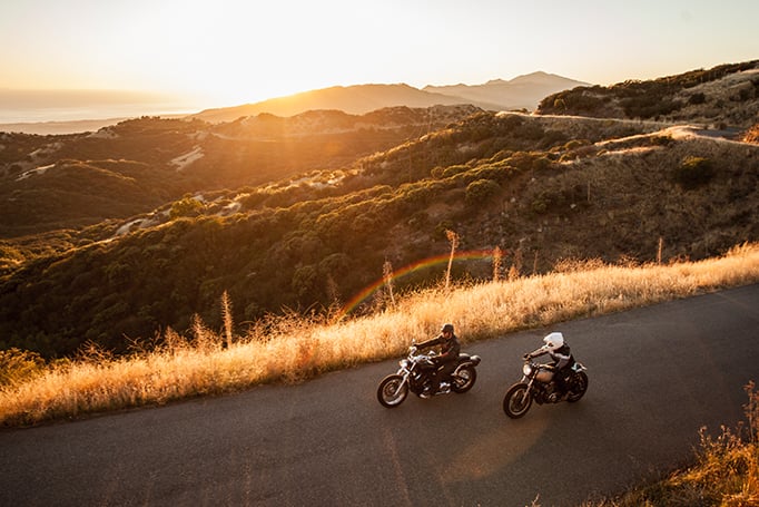 Two motorcyclists driving in the sunset